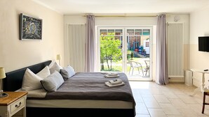 A bedroom with a bed, bedside table, lamp, and a view of the outside. - Himmelreich Rügen (Zirkow)