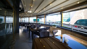 Un restaurante moderno con una barra alargada, sillas altas y grandes ventanales con vista a la calle.