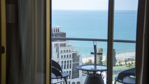 Vista desde una ventana sobre una playa y un edificio de estilo arquitectónico moderno.