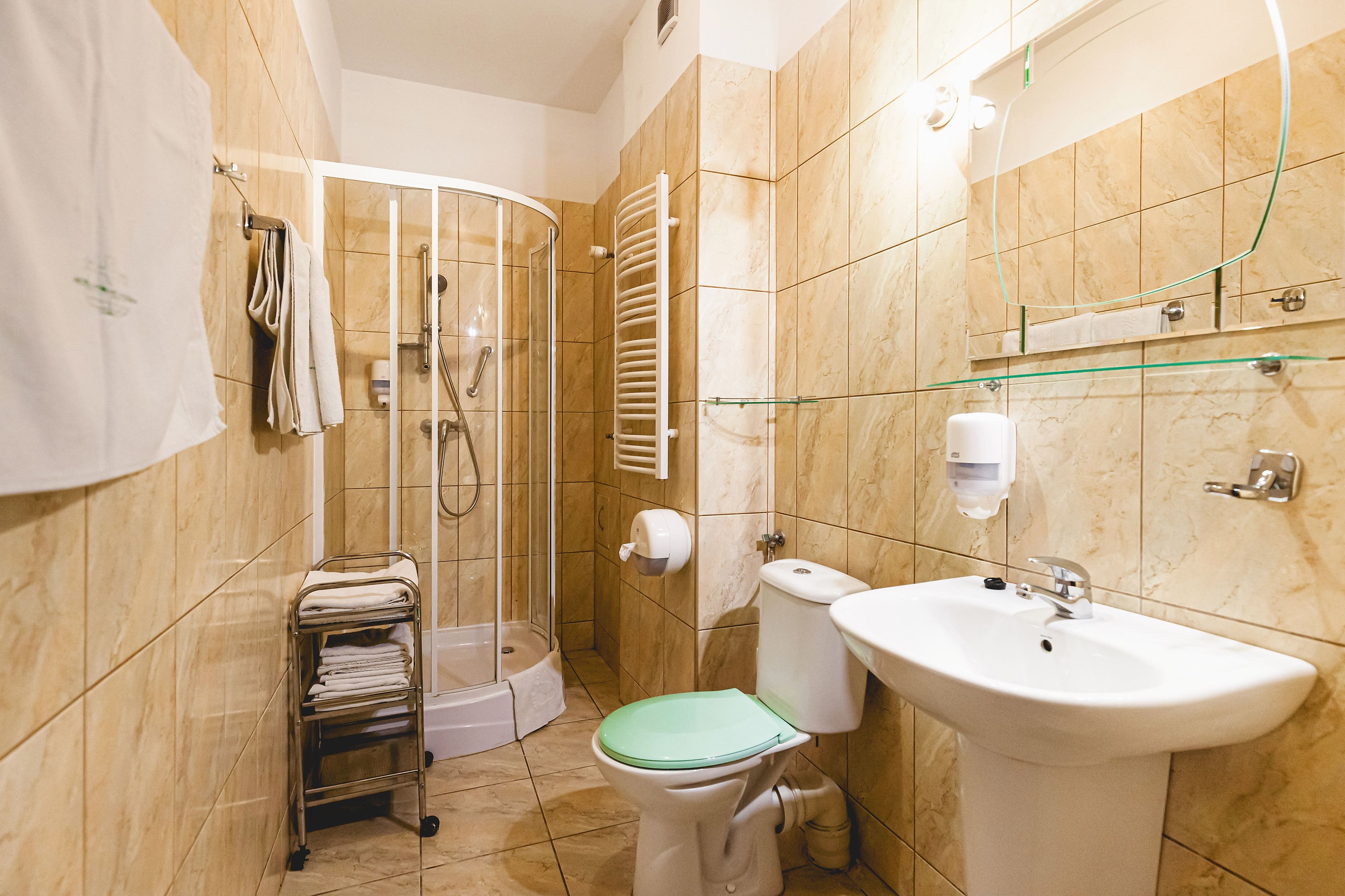 Un baño con cabina de ducha de vidrio, inodoro, lavamanos y perchero para toallas.