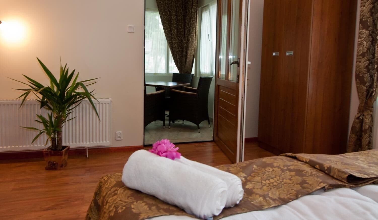 Quarto de hotel com cama, planta em vaso, espelho no banheiro e vista do banheiro.