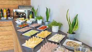 A buffet table with various food items and small potted plants.