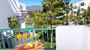 Ein Balkon mit Holztisch, gedeckt für eine Mahlzeit, mit einem Teller Essen und zwei Gläsern Orangensaft.