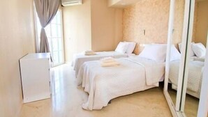 Ein Hotelzimmer mit zwei Betten, einem Schreibtisch und einem Fenster mit Vorhängen.