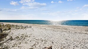 Een strand met een houten omheining, zand en de oceaan.