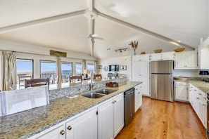 A modern kitchen with granite countertops, stainless steel appliances, and white cabinetry.