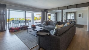 Una sala moderna con un sofá gris, una mesa de centro y un ventanal que ofrece vistas al exterior.