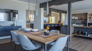 Un comedor moderno con una mesa de madera, sillas tapizadas de color gris e iluminación colgante.