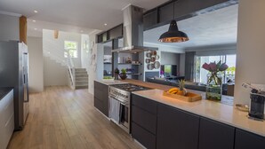 Una cocina moderna con una isla central, electrodomésticos de acero inoxidable y una escalera que sube a un nivel superior.