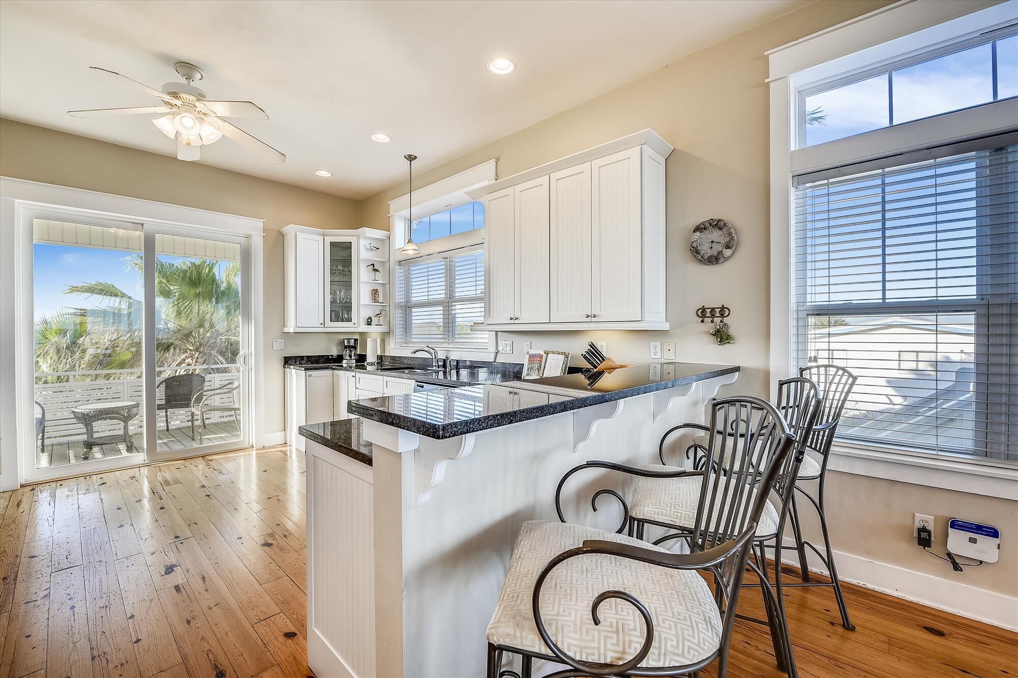 A spacious kitchen with a large island, white cabinetry, and a view of the outdoors.