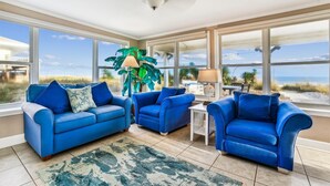 Una habitación luminosa con ventanas amplias, un ventilador de techo y vista a la playa.