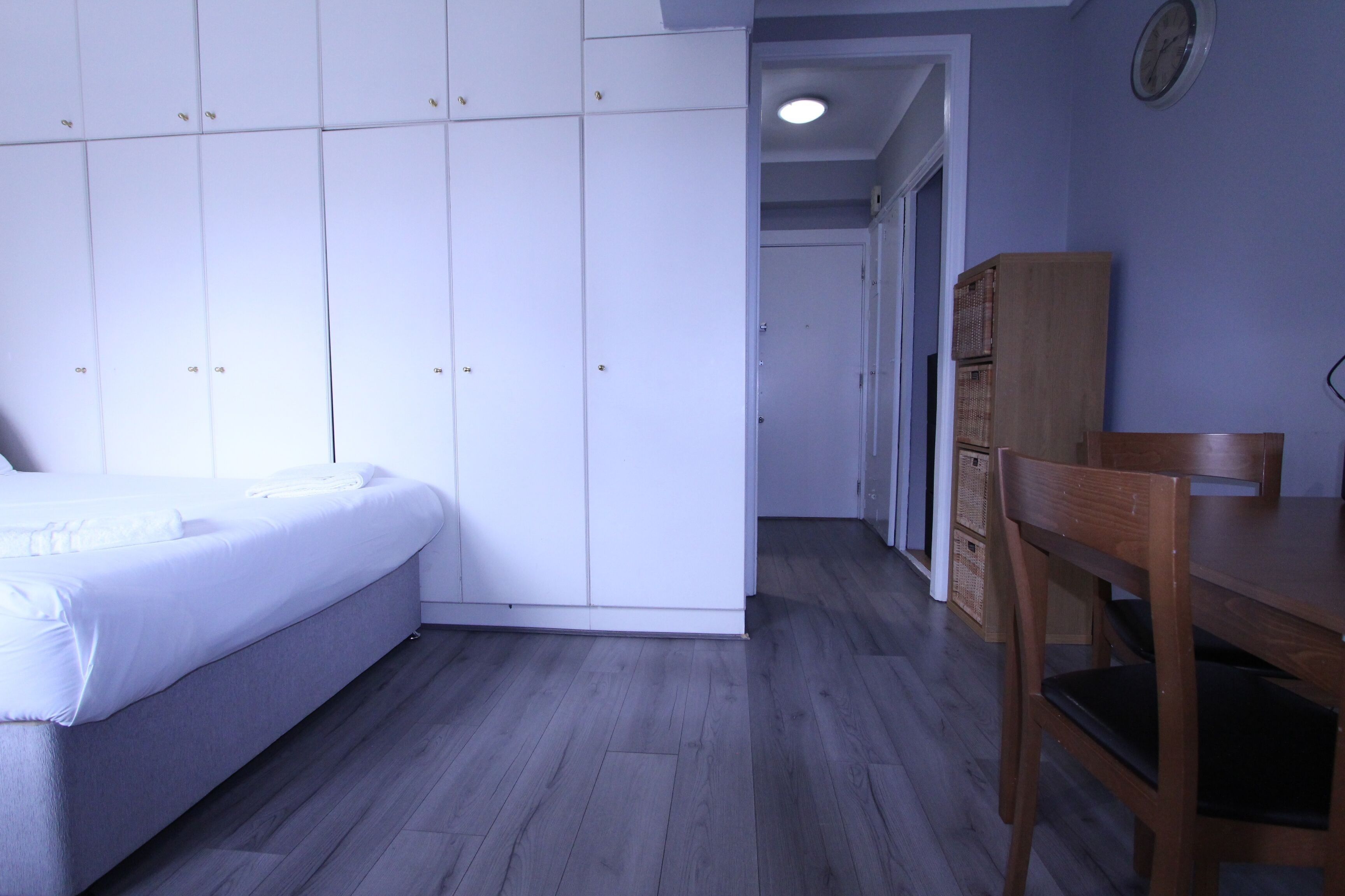 A bedroom with a bed, a wardrobe, a desk, and a chair.