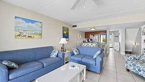 A living room with two blue sofas, a white coffee table, and a ceiling fan.