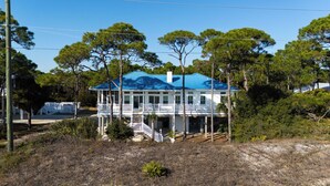 A two-story house with a blue roof, white exterior, and a covered porch with a white railing. - WELCOME to our house, HEATWAVE for an unforgettable beach experience on beautiful St. George Island. (St. George Island)