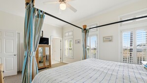A bedroom with a bed, curtains, a ceiling fan, and a view of the outside. - WELCOME to our house, HEATWAVE for an unforgettable beach experience on beautiful St. George Island. (St. George Island)