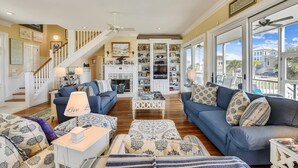 A spacious living room with a fireplace, a staircase, and a large window with a view of the outside.