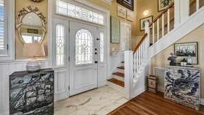 A foyer with a double door, a staircase, and nautical-themed artwork.