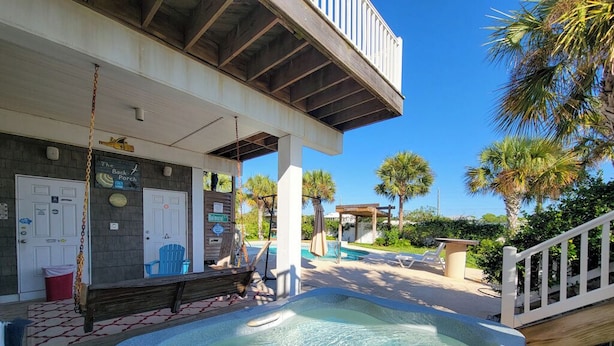 A pool area with a hot tub, lounge chairs, and a wooden deck.