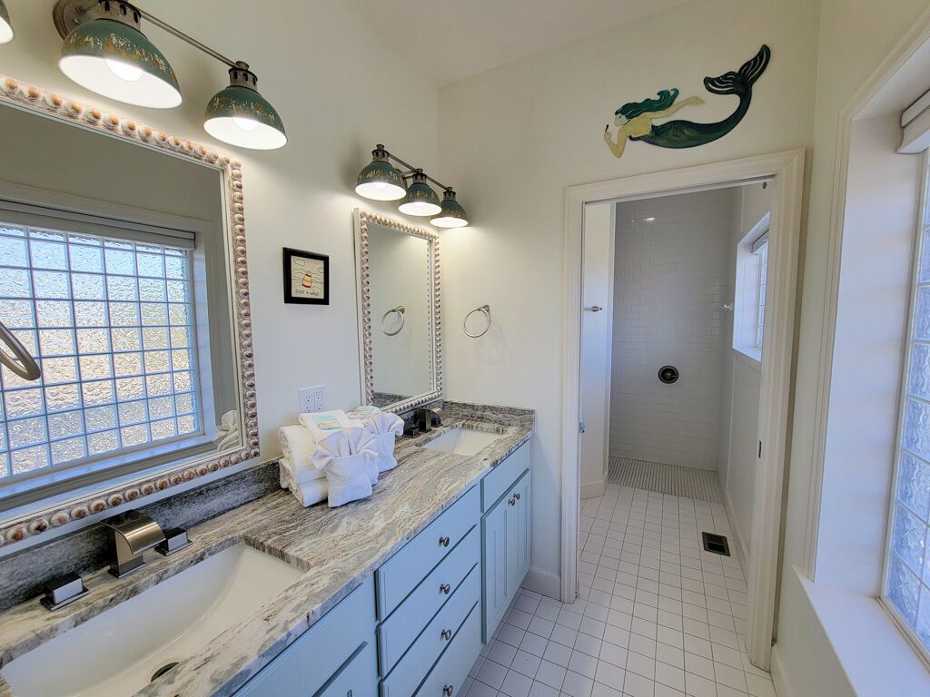 A bathroom with a large mirror, vanity with a sink, towel rack, and a shower area.