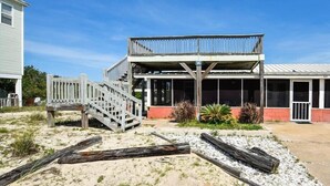 A beachfront building with a wooden deck and a covered area.