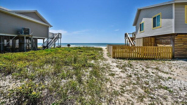 A beachfront property with two wooden houses, a sandy beach, and a clear blue sky.