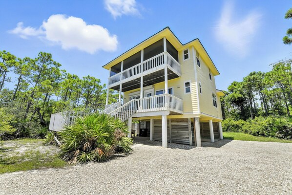 A two-story building with a balcony on the upper floor, surrounded by greenery.