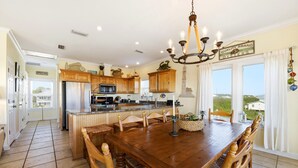 Una cocina amplia con armarios de madera, una isla central y un comedor con una araña.