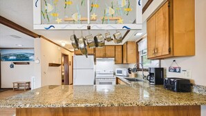 A kitchen with granite countertops, wooden cabinets, and hanging pots.