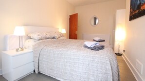 A bedroom with a bed, nightstand, lamp, and a painting on the wall. - Cosy One Bedroom Apartment- Marble Arch (London)