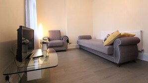 A modern living room with a glass coffee table, two sofas, a flat-screen TV, and a lamp. - Cosy One Bedroom Apartment- Marble Arch (London)