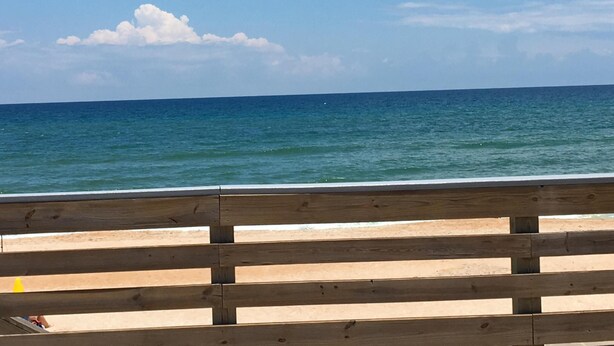 A wooden beach barrier with a clear view of the ocean and a sandy beach.