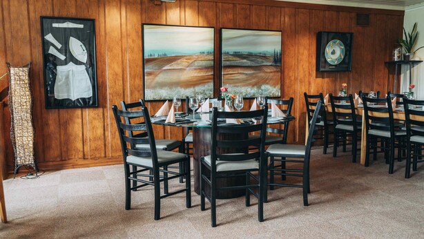 A dining area with a round table, multiple chairs, and artwork on the walls. - Skaslien Gjestgiveri (Grue)