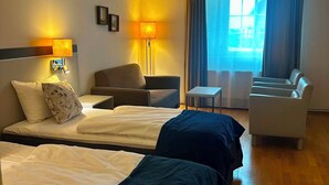 A hotel room with two beds, a desk, a chair, and a sofa. - Skaslien Gjestgiveri (Grue)