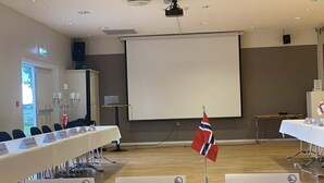 A conference room with a long table, nameplates, and a projector screen. - Skaslien Gjestgiveri (Grue)
