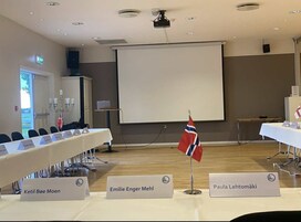 A conference room with a long table, nameplates, and a projector screen.