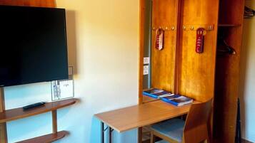 A room with a bed, a desk with a chair, a television, and a wardrobe.