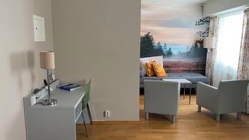 A modern room with a desk, two chairs, a sofa, and a large window with a view of trees.