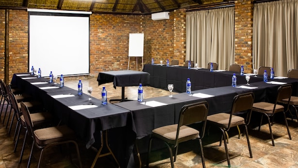 A conference room with a long table, chairs, water bottles, and a projector screen. - Elgro River Lodge (Potchefstroom)