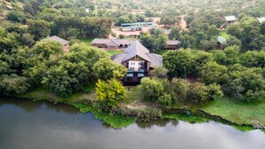 An aerial view of a lodge with multiple buildings surrounded by dense forest and hills. - Elgro River Lodge (Potchefstroom)