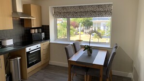 Une cuisine moderne avec des meubles en bois, un four encastré et une fenêtre donnant sur l’extérieur.