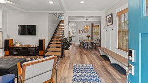 A modern living room with a staircase, wooden flooring, and a dining area with a table and chairs. - PRISTINE PROPERTY IN PRIME LOCATION — CHARMING ☆ SAFE ☆ WALK TO EVERYTHING (Nashville)