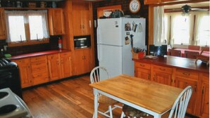 Una cocina con armarios de madera, un refrigerador blanco y una mesa de comedor de madera con sillas.
