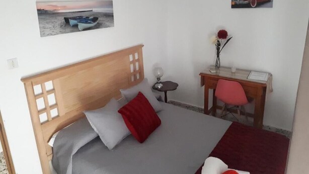 A bedroom with a wooden bed, a desk, a chair, and two wall-mounted pictures. - Lunares y Salinera (Albanchez de Magina)