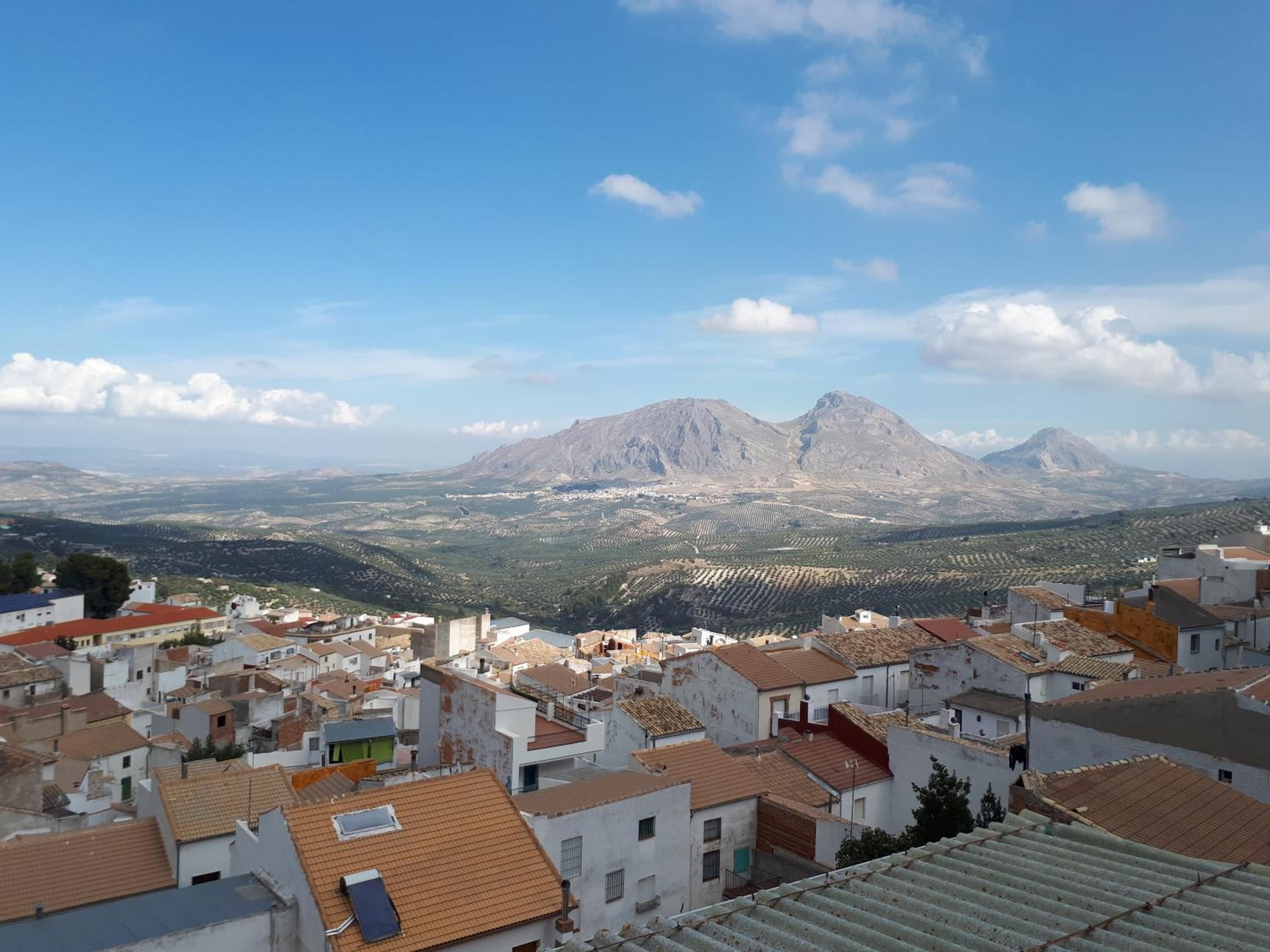 Un pueblo de edificios blancos y tejados de teja, rodeado de montañas.