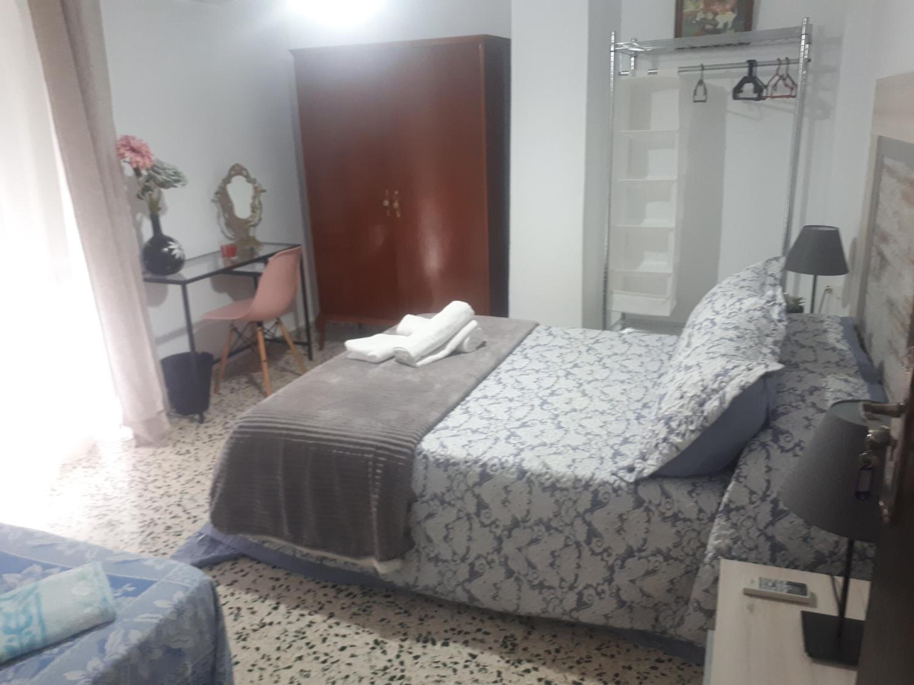 A bedroom with a bed, a wardrobe, a desk, and a chair.