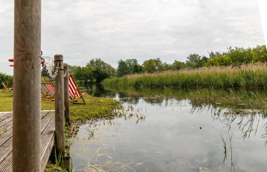 A calm body of water with a wooden dock and red and white striped barriers.
