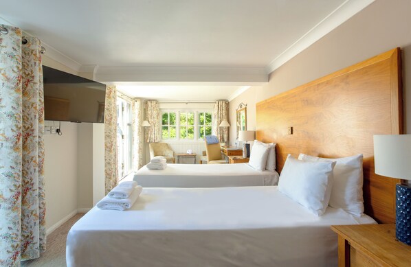 A hotel room with two beds, a wooden headboard, a desk with a chair, a TV, and a window with curtains. - Thorpeness Golf Club and Hotel (Leiston)