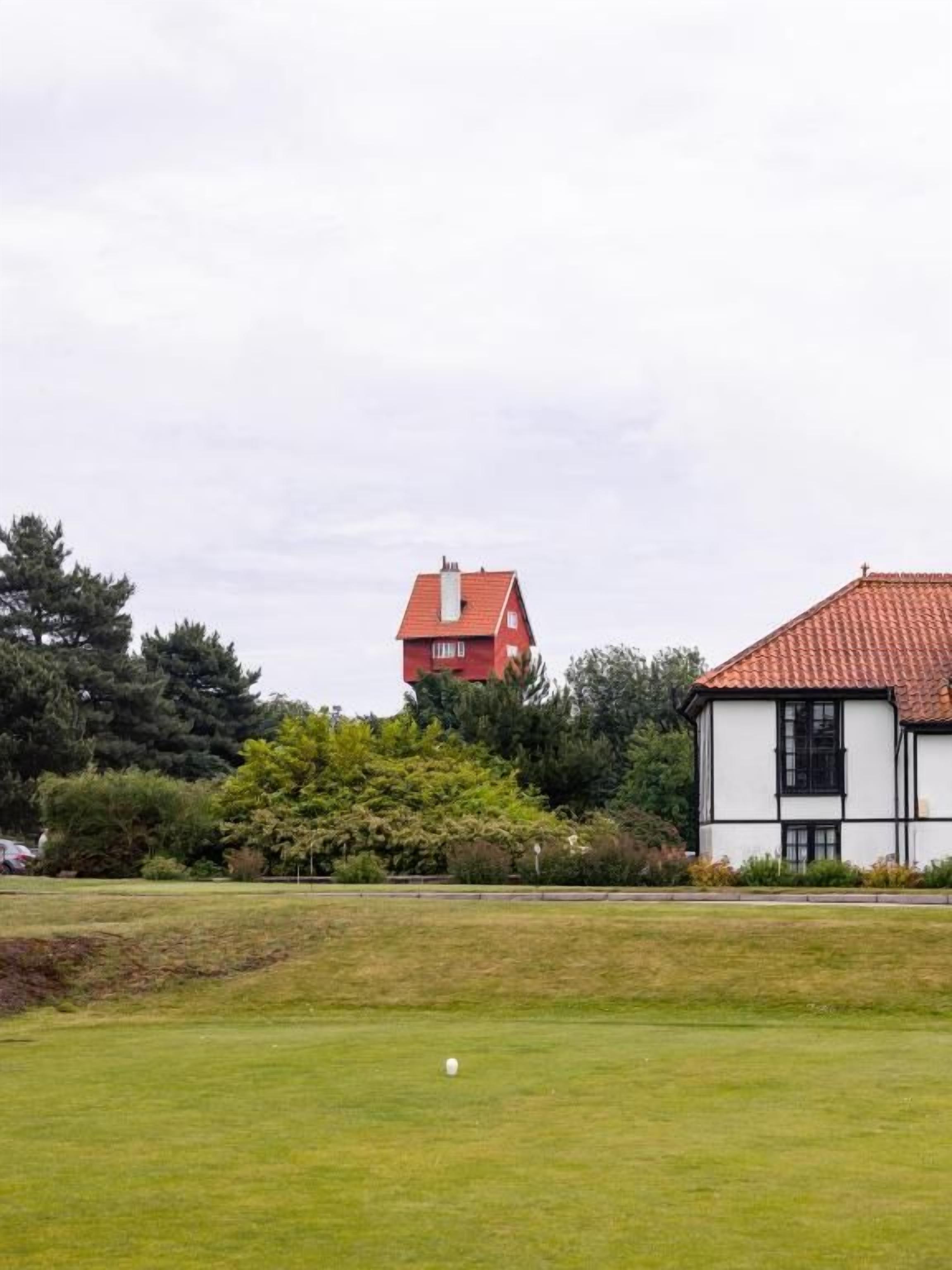 A golf course with a red-roofed building in the background.
