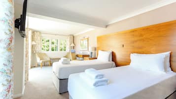 A hotel room with two beds, a TV, a desk with a lamp, and a chair.