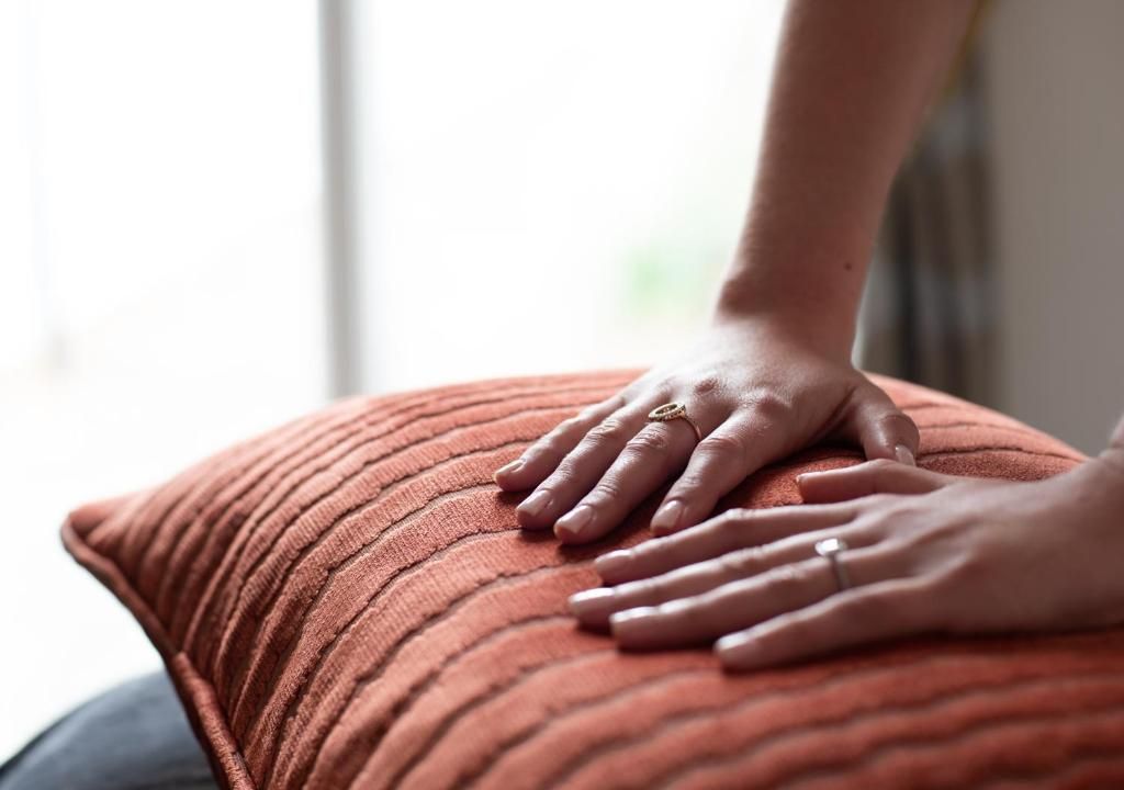 A person's hands resting on a textured, ribbed pillow.